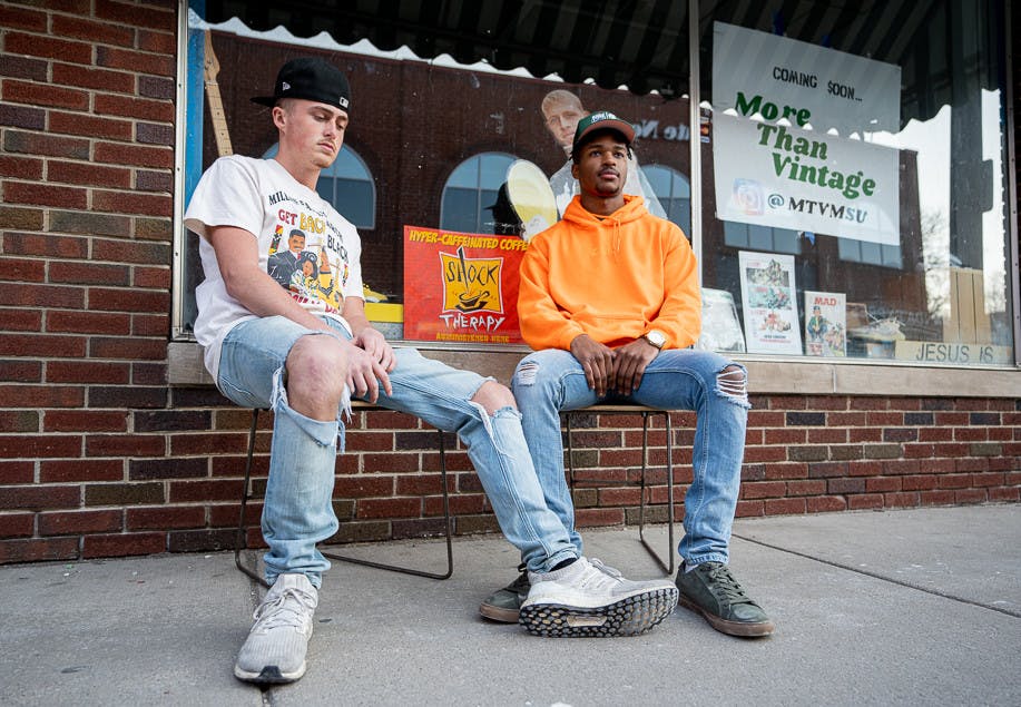 <p>Michigan State sophomore and founder of More Than Vintage, Louis Azor (right), sits outside his new store location with best friend and general manager Noah Hurley (left) on Mar. 16, 2022.</p>