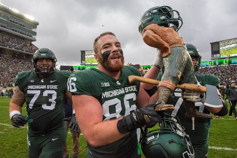 <p>Graduate student defensive end Drew Beesley carries the Paul Bunyan trophy after the Spartans&#x27; 37-33 win against the Wolverines on Oct. 30, 2021.</p>