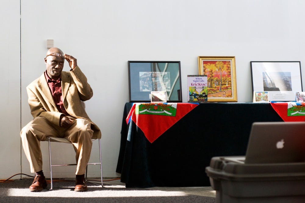 Lansing resident Pierre Balthazar sits down to rest while he waits for people to stop at his booth Wednesday at Brody Hall. Balthazar, who was born and raised in Haiti, was part of the "Haiti: One Year Later" event aimed at raising awareness and funds for the still-struggling country. Kat Petersen/The State News