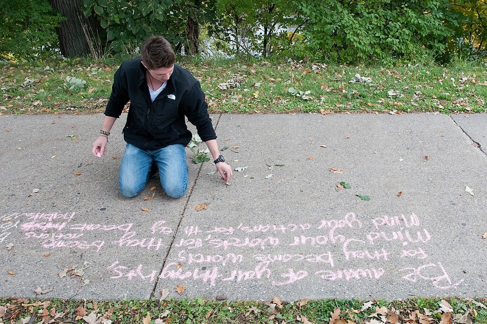 <p>Philosophy junior Robert Nebergall writes a poem Oct. 1, 2014, on a sidewalk behind Shaw Hall. "Thoughts dictate who you are," Nebergall said about what the poem he wrote meant to him. Dylan Vowell/The State News</p>