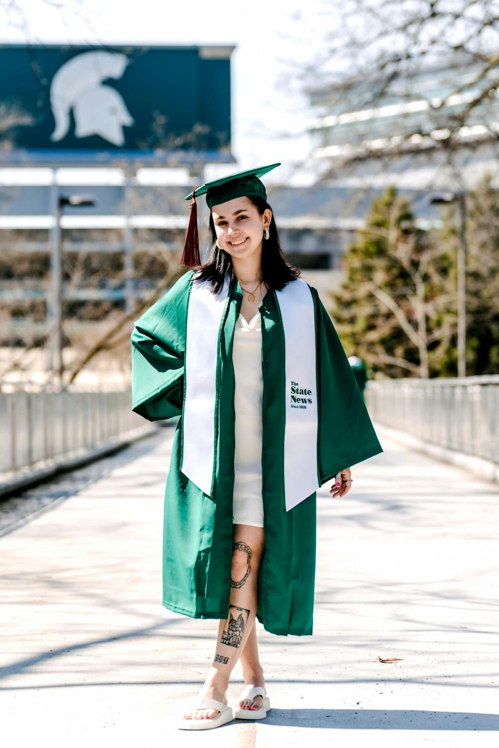 <p>The State News&#x27; women&#x27;s basketball beat reporter and Michigan State journalism senior Sara Tidwell stands in her cap and gown in front of Spartan Stadium.</p>