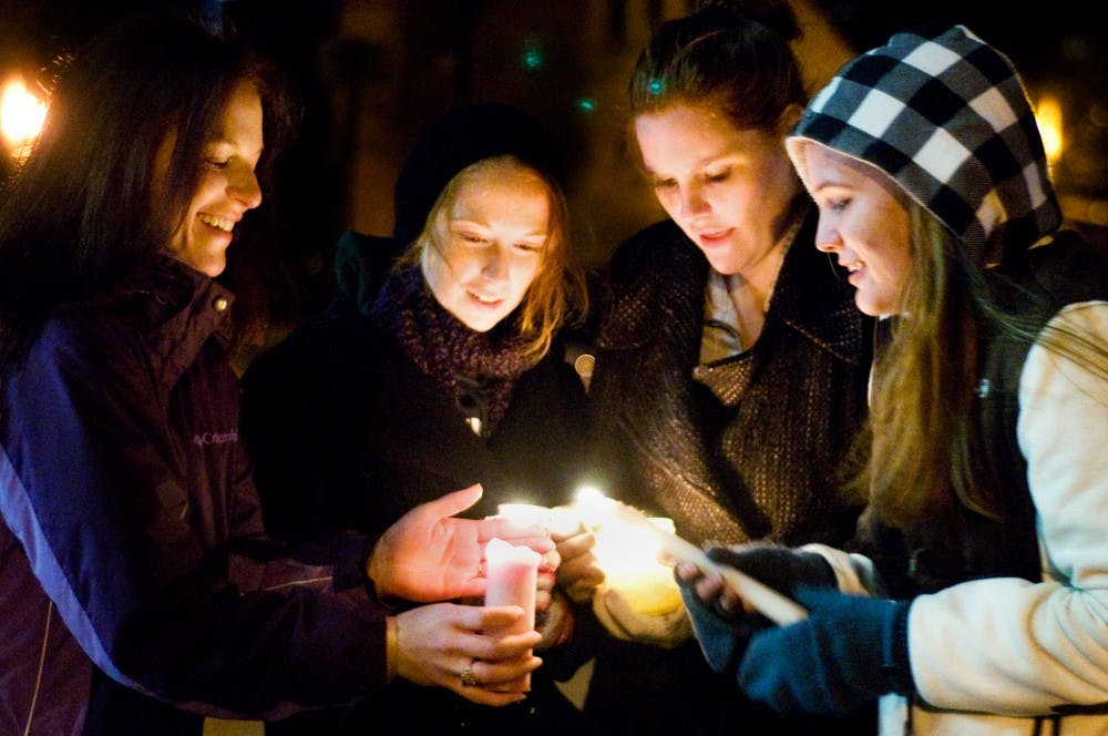 From left, social work seniors Carolyn Tobey, Kelsey Crimmins, Jessica Greenfield, and Mindy Warner light up candles outside Baker Hall Friday night. The MSU School of Social Work held the candlelight vigil for the victims of the child sexual abuse allegations at Penn State. Justin Wan/The State News