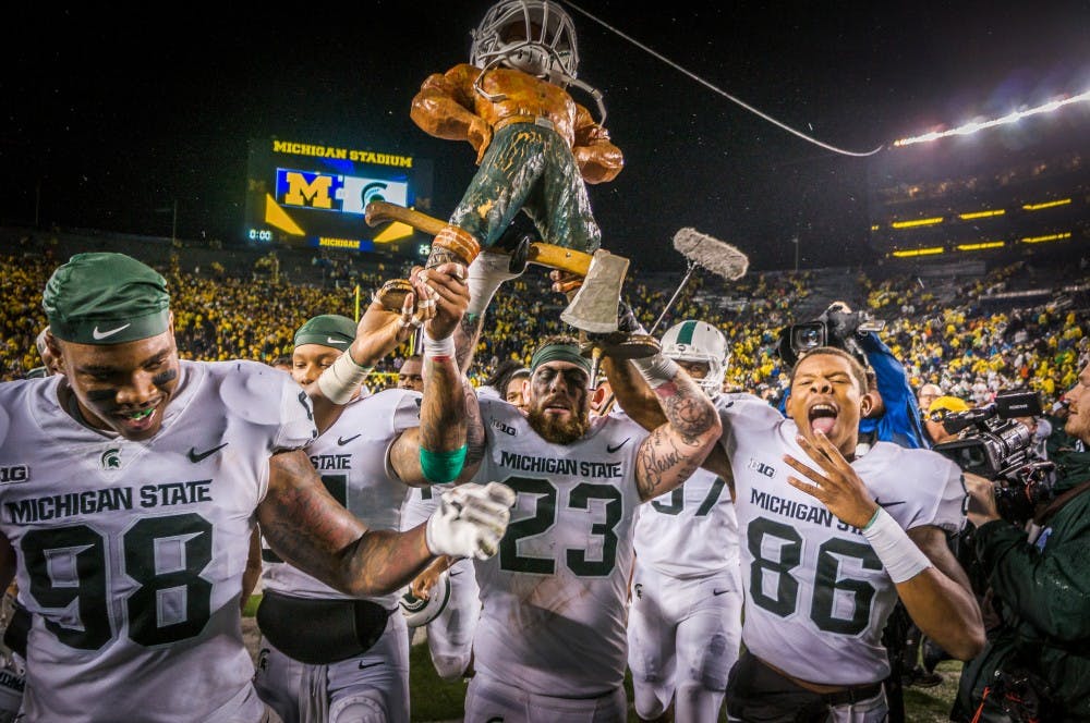 <p>Senior linebacker Chris Frey Jr. (23) celebrates with the Paul Bunyan Trophy after the game against Michigan on Oct. 7, 2017 at Michigan Stadium. The Spartans defeated the Wolverines, 14-10.</p>