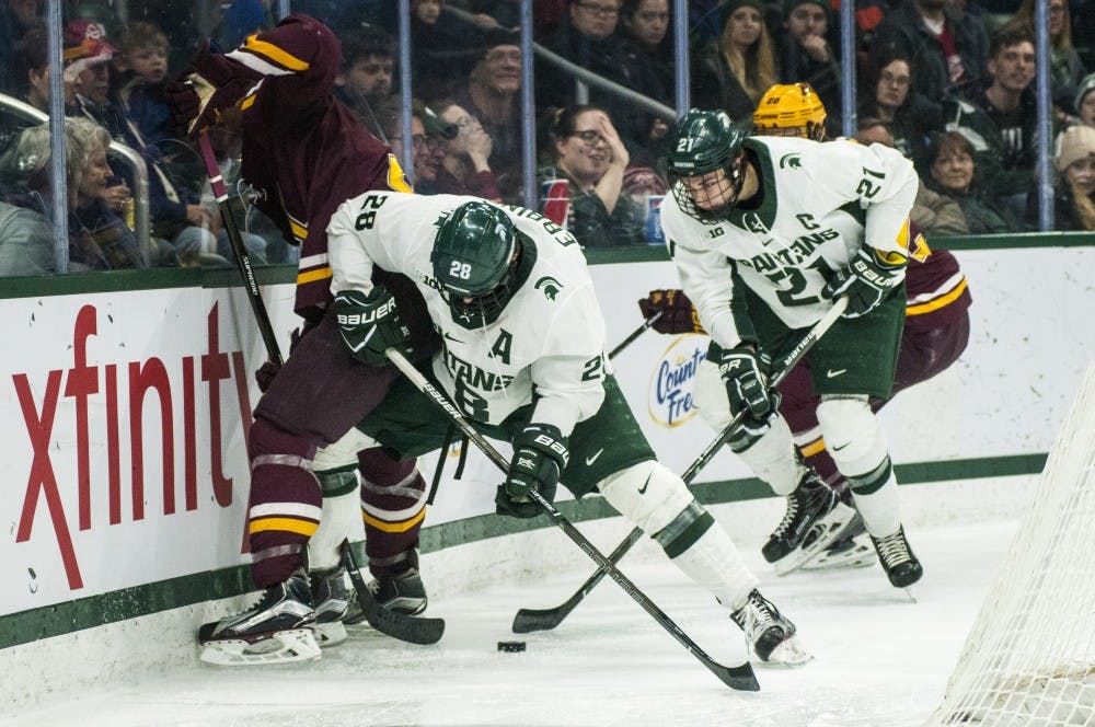 Senior forward Thomas Ebbing (28) and senior forward oe Cox (21) fight for the puck during the second period in the game against Minnesota on Dec. 9, 2016 at Munn Ice Arena. The Spartans were defeated by the Gophers, 4-2.