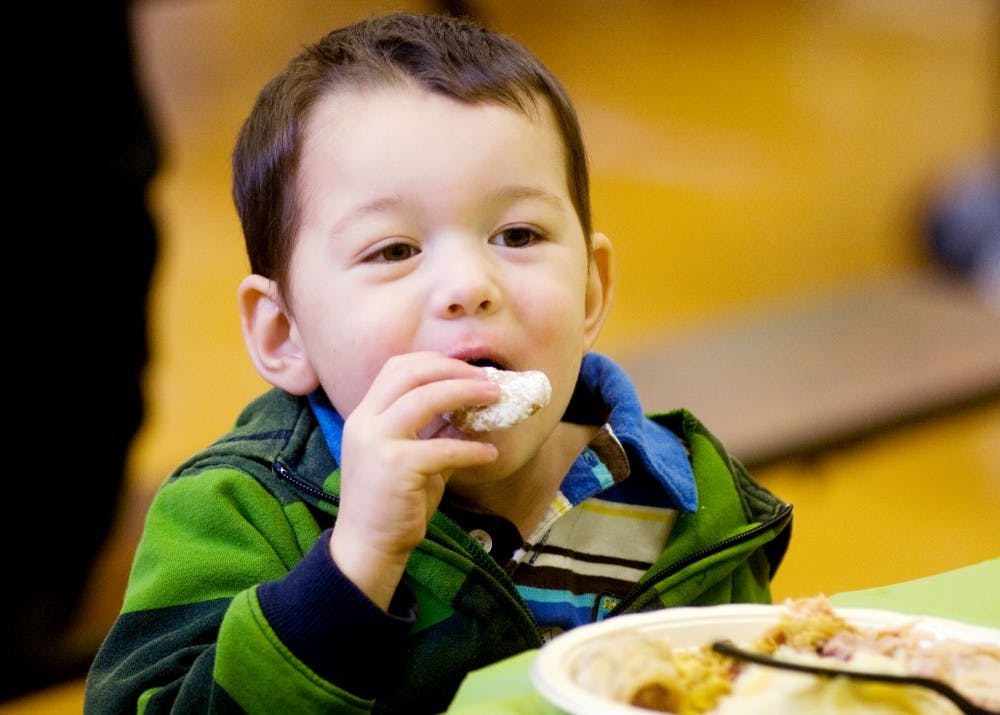 Colin Smith, 4, bites into one of the many deserts available at the Thanksgiving Feast at Red Cedar Elementary School on Sunday afternoon. This year marked the first Thanksgiving Feast hosted by the Community Relations Coalition. Anthony Thibodeau/The State News