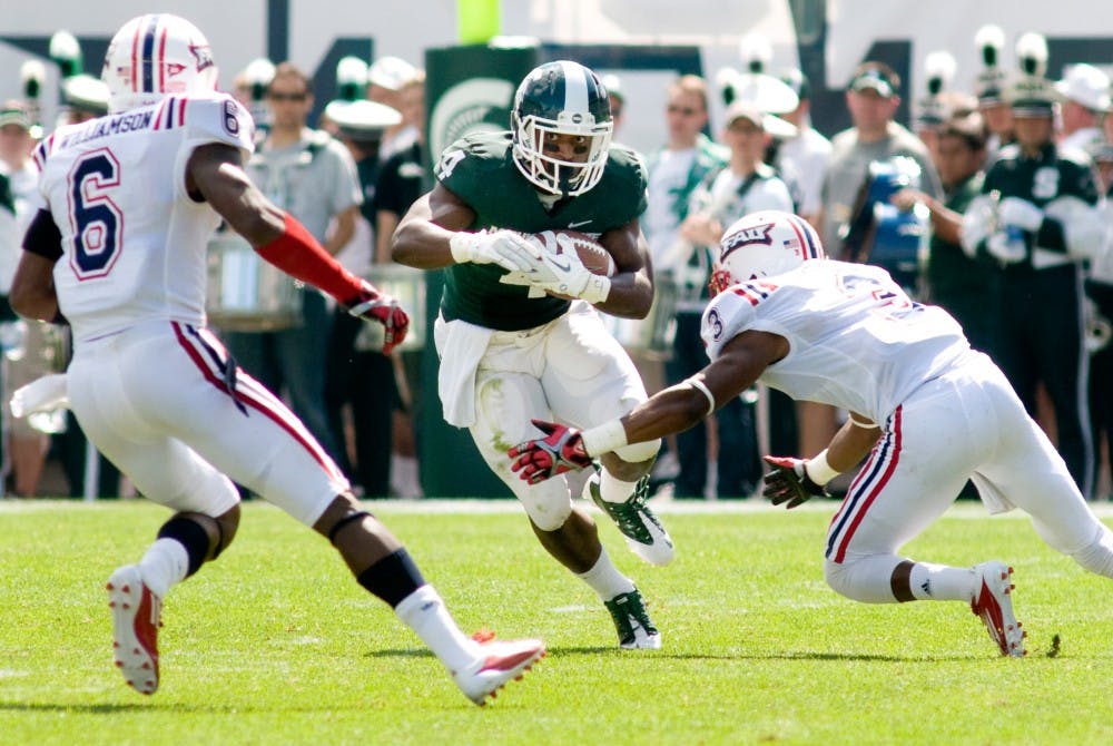 Junior running back Edwin Baker runs with the ball through Florida Atlantic defensive backs Demetrius Williamson, left, and Keith Reaser, right, during the second half of Saturday's game in Spartan Stadium. Baker gained 51 yards rushing in the game. Lauren Wood/The State News