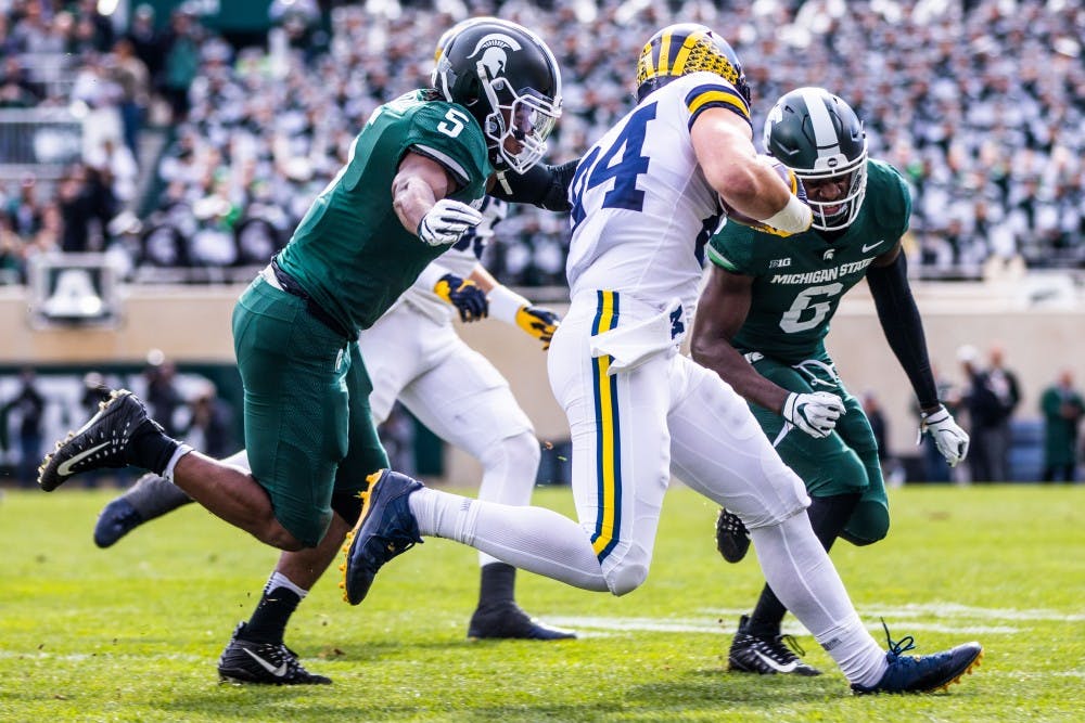 <p>MSU defenders Andrew Dowell (5) and David Dowell (6) tackle Michigan tight end Sean McKeon (84) during the game at Spartan Stadium Oct. 20. The Wolverines defeated the Spartans, 21-7.</p>