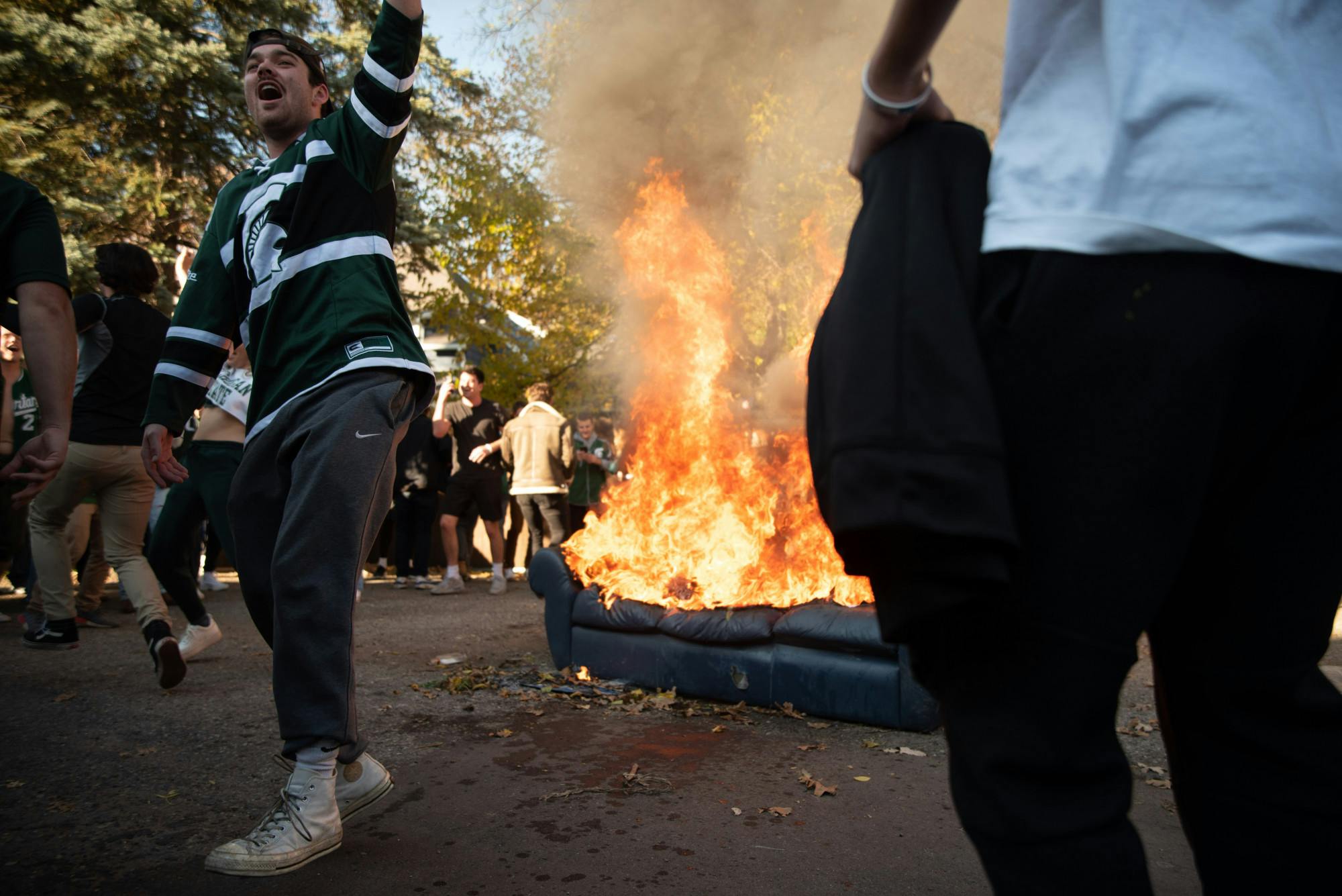 <p>Michigan State University students partying near a burning couch in an alley off of Division Street on Oct. 31, 2020.</p>