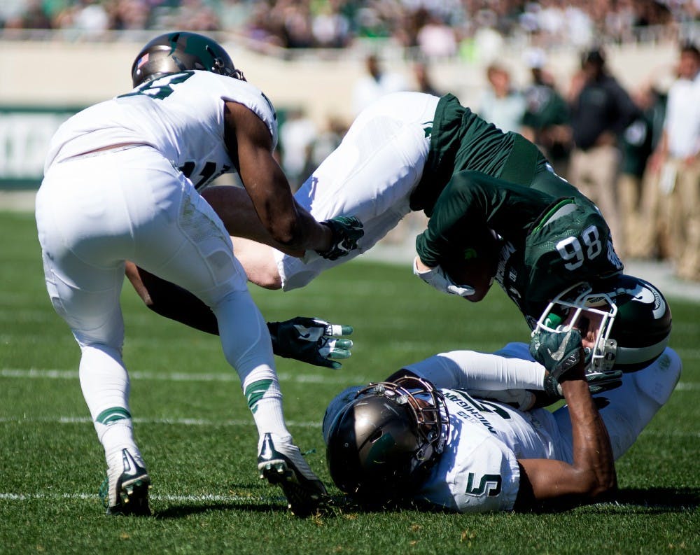 Senior wide receiver Matt Macksood is sacked by sophomore wide receiver Darrel Stewart Jr., left, and sophomore linebacker Andrew Dowell, 5, during the Green and White scrimmage on April 23, 2015 at Spartan Stadium. The White team defeated the Green team, 14-11. 