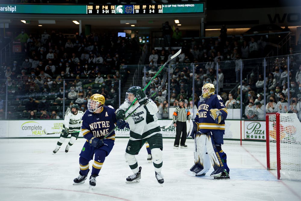 <p>Michigan State junior Erik Middendorf battling against Notre Dame senior Spencer Stastney as the puck comes their way on Feb. 18, 2022. Spartans lost 2-1 against Notre Dame. </p>