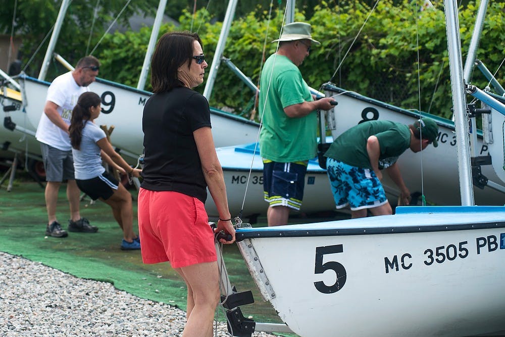 <p>Portland, Mich., resident Chris Flaga pulls a sail boat forward for preparation June 26, 2014, at the Sailing Center off the shore of Lake Lansing. Flaga was one the participants to complete the latest sailing course. Hayden Fennoy/The State News</p>