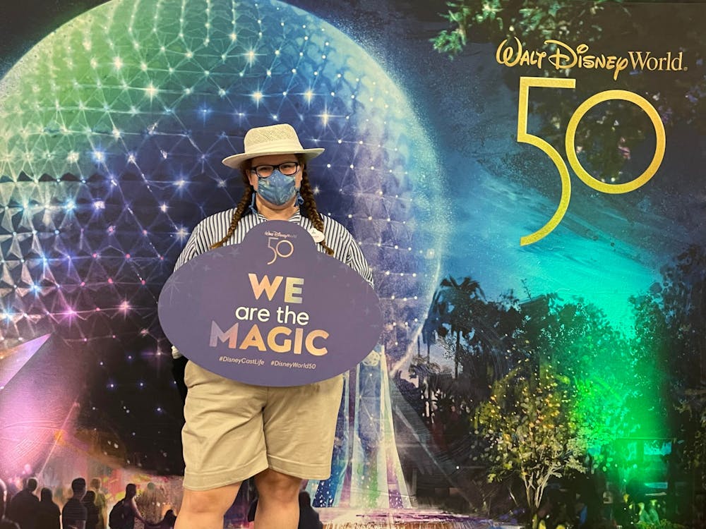 <p>Hospitality business junior Linsey Nichols stands holding a &quot;We are the magic&quot; sign during her internship with Disney.</p>