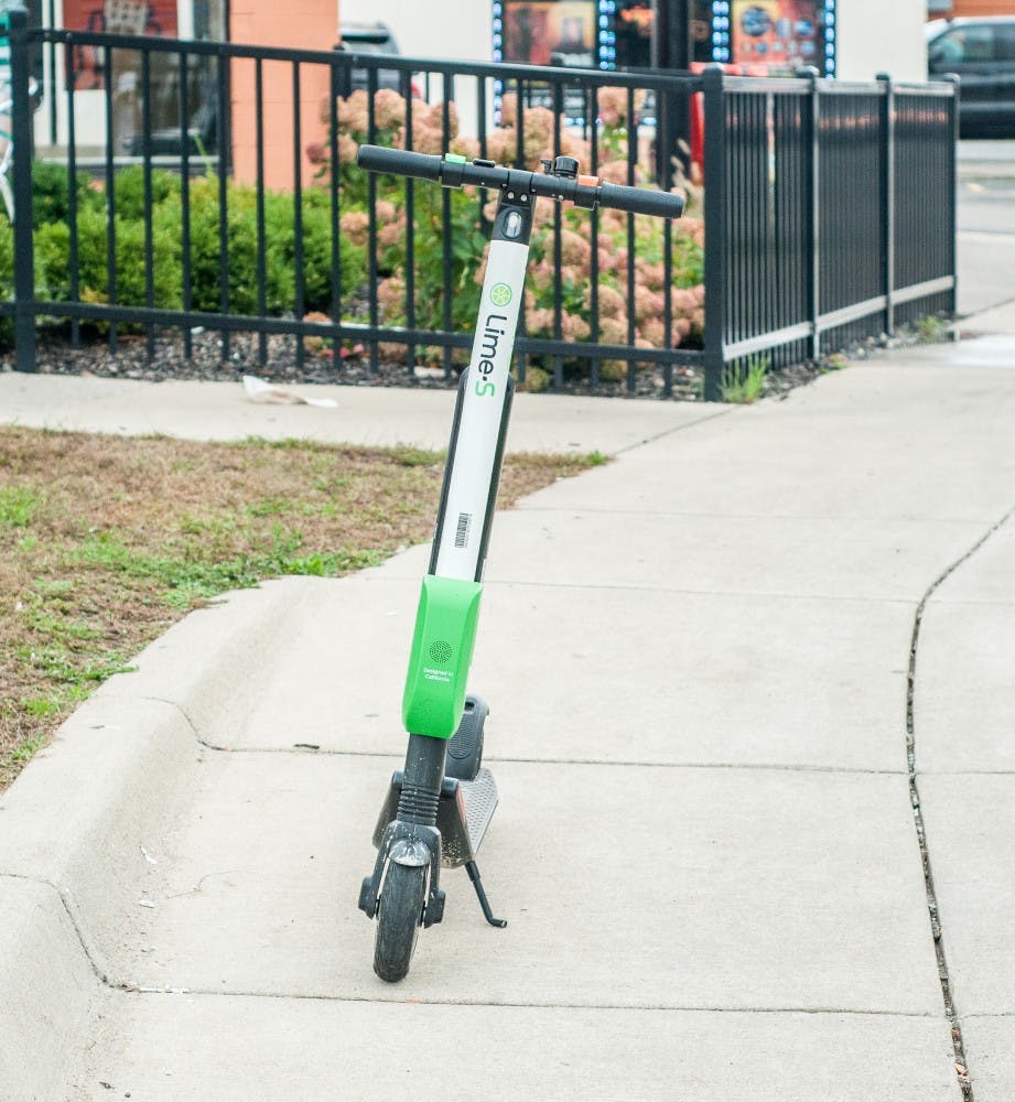 <p>A Lime scooter is pictured parked on the sidewalk on Grand River Avenue.</p>