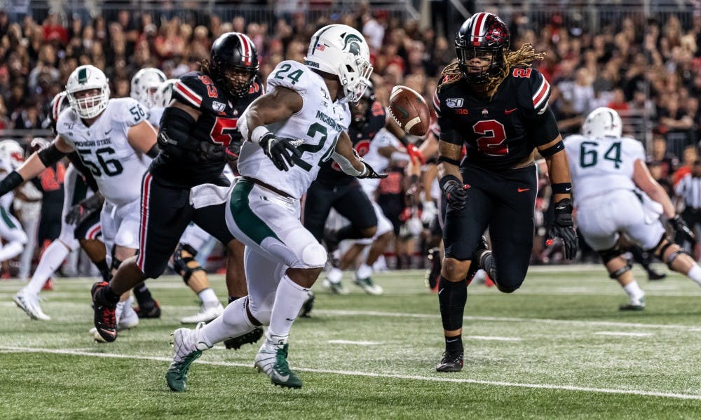 <p>Then-freshman running back Elijah Collins (24) fumbles a pitch from then-senior quarterback Brian Lewerke against Ohio State. The Buckeyes defeated the Spartans, 34-10, on Oct. 5, 2019, at Ohio Stadium.</p>