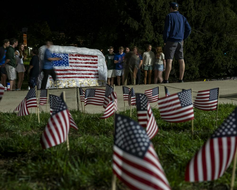 Members of MSU Young Americans for Freedom and MSU College Republicans gather around the Rock after preparing a 9/11 memorial at Michigan State University in East Lansing, Mich., Thursday, Sept. 10, 2026. The organizations placed 2,977 American flags around the Rock, one for each victim killed in the Sept. 11, 2001, terrorist attacks, to mark the 25th anniversary of the attacks.