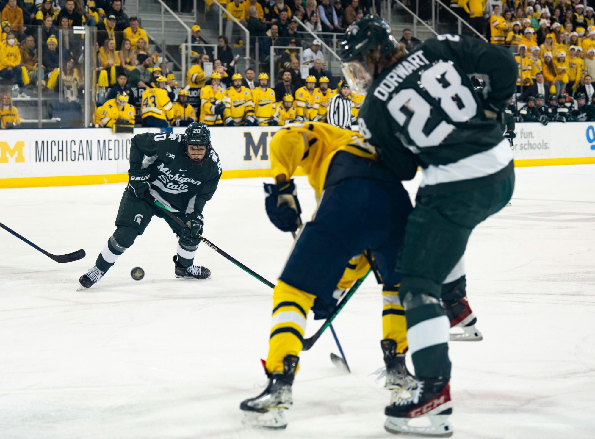 Freshman forward Daniel Russell (20) attempts to keep the puck out of University of Michigan's hands in a game at Yost Ice Arena on Dec. 10, 2022. 