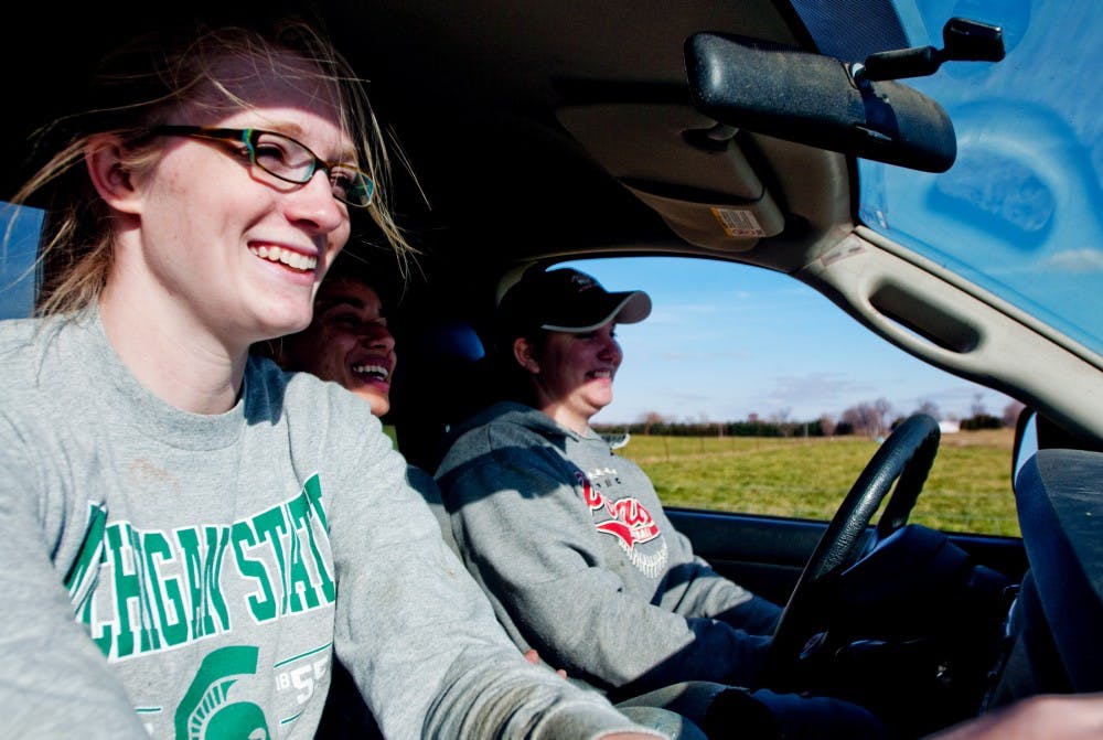 Plant and soil sciences junior Maddie Hale rides in a work truck with fellow students, animal science senior Amber Tompkins and animal science junior Jessica Ernest last Friday afternoon on the south campus farms. The three were going to check on one of the flocks of sheep of the Sheep Teaching and Research Center. Josh Radtke/The State News