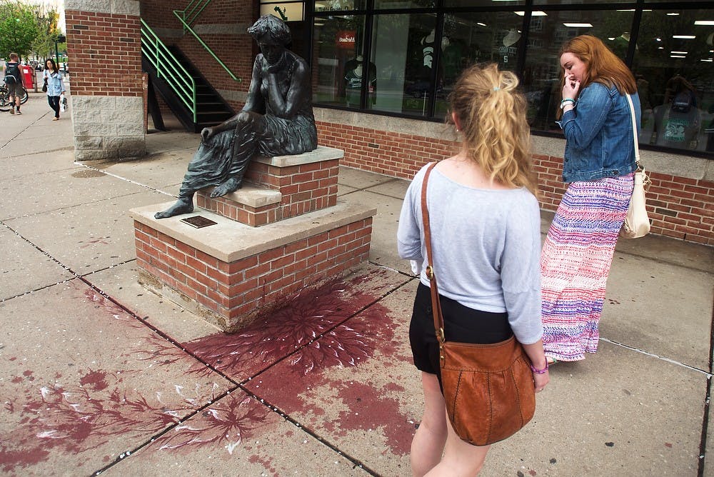 <p>Education junior Kenna Holsington, left, and Caitlin Hamilton, right, observe a public art display May 12, 2014, on Grand River Ave., in front of Bubble Island. The art was created by Pakistani artist Imran Qureshi in locations throughout East Lansing. Hayden Fennoy/The State News</p>