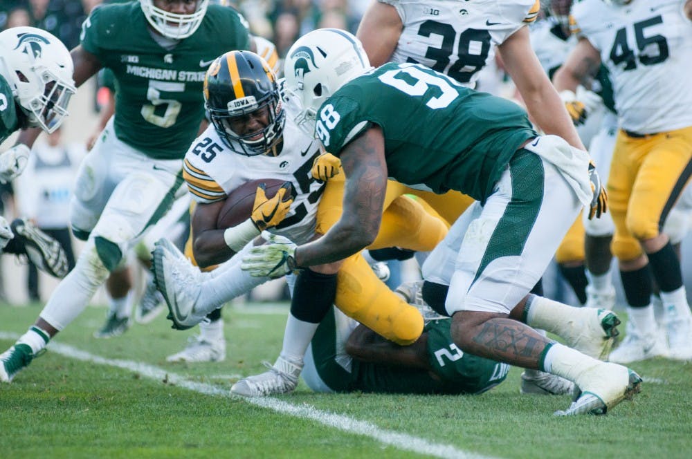 <p>Senior running back Akrum Wadley (25) braces for a hit from senior defensive end Demetrius Cooper (98) during the game against Iowa on Sept. 30, at Spartan Stadium. The Spartans defeated the Hawkeyes 17-10.</p>