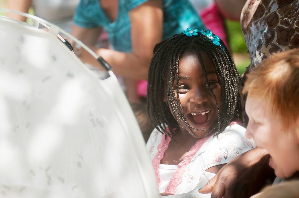 	<p>Lansing resident Corinne Williams, 6, laughs alongside Lansing resident Anderson Stevens, 7,  as they stick their hands into a bee tent June 23, 2013, during <span class="caps">MSU</span> Bee Palooza at the <span class="caps">MSU</span> Horticulture Demonstration Gardens. The event was hosted in order to teach children about bees and to promote bee health. Danyelle Morrow/The State News</p>