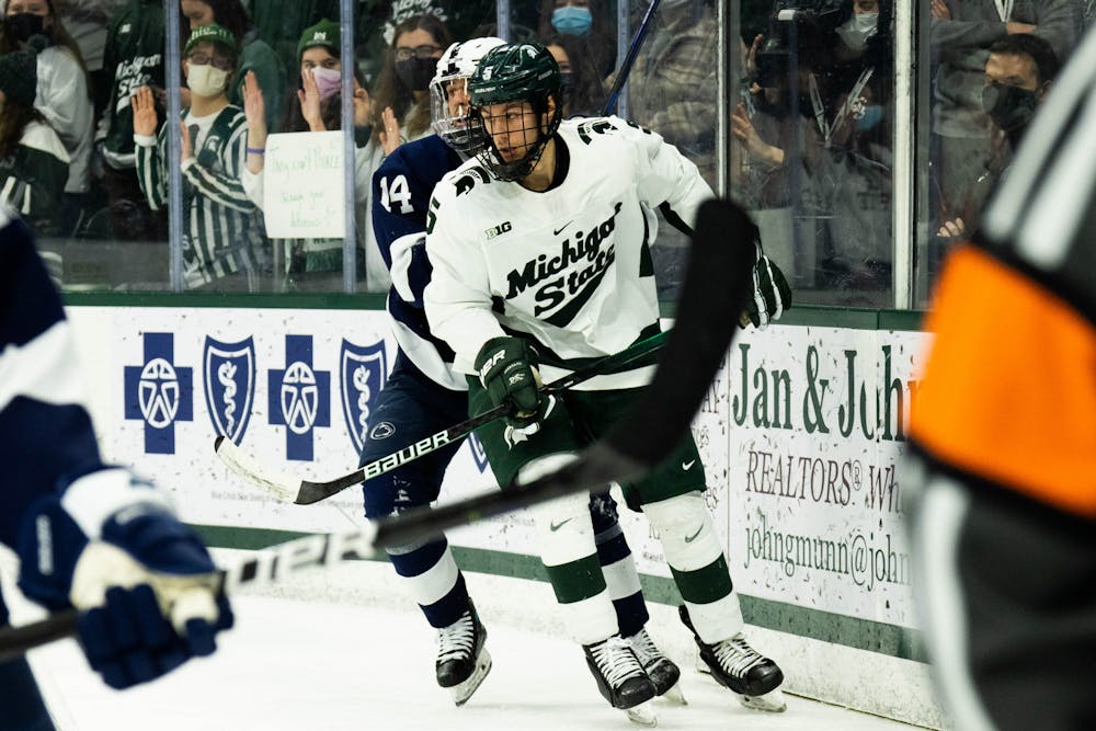 <p>Sophomore defenseman Powell Connor (5) fights off Penn State senior forward Ben Copeland (14) during a game at Munn Ice Arena on Feb. 25, 2022. The Spartans fell to the Nittany Lions with a score of 5-3. </p>