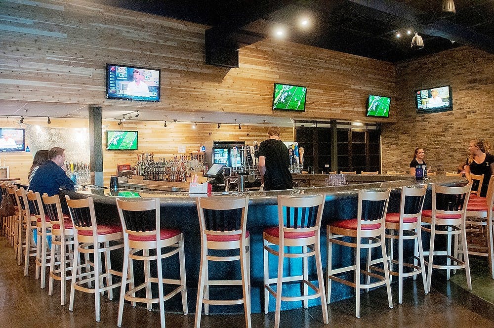 <p>Customers and servers mingle Sept. 17, 2014, at Chandler TapHouse on 16800 Chandler Rd. in East Lansing. The bar participates in happy hour every weekday from 3-7pm. Jessalyn Tamez/The State News</p>