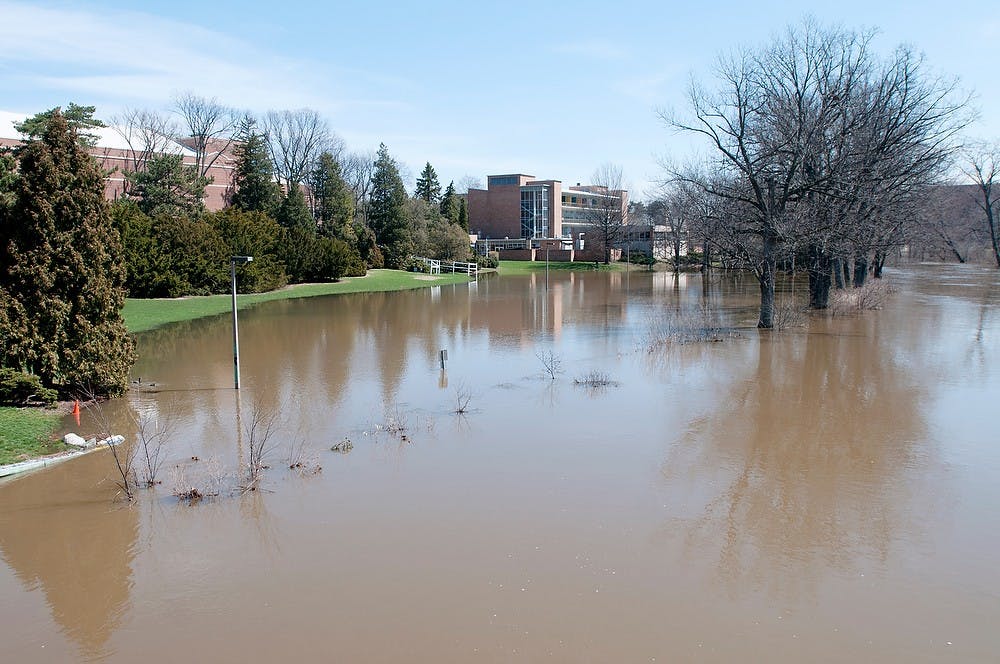 	<p>The flooded Red Cedar River encroaches on the lawn space behind the Auditorium on Sunday. The river crested at 7.9 feet. Julia Nagy/The State News</p>