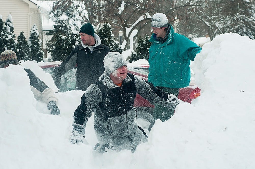 <p>Construction management Alec Sgrow, back left, turf grass management senior Evan Herman, back right, and supply chain management senior Nick Gonyea stand around the collapsed igloo after jumping on top of it Jan. 6, 2014, on the 200 block of Durand. The roommates spent several hours building the igloo. Danyelle Morrow/The State News</p>