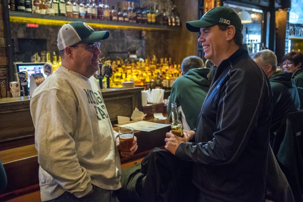 Boston resident and 1991 MSU alumnus David Reynolds, left, enjoys a beer with his brother, Dan, also of Boston, before the Big Ten Men's Basketball semifinal game between Michigan State and Michigan on March 3, 2018 at Mustang Harry's in New York. Between one and two hundred MSU fans and alumni gathered at Mustang Harry's before the game. (Nic Antaya | The State News)