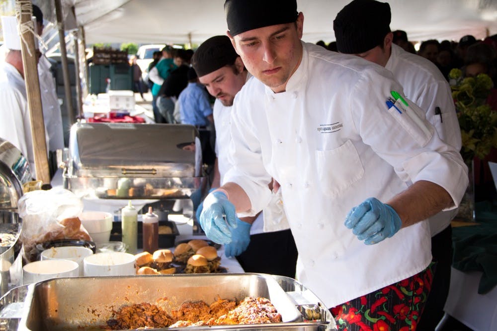 Communications senior and cook for Spartan Signature Catering, Jeremy Epley makes pulled pork sandwiches during the first-ever Taste of East Lansing event hosted by the city of East Lansing's Community Relations Coalition Saturday evening at Ann Street Plaza The event featured local food vendors, games, arts & crafts. Aaron Snyder/The State News 