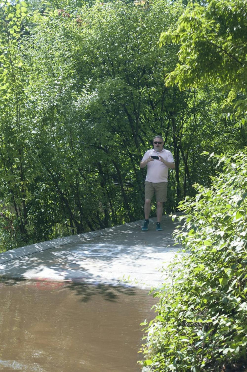 Langsburg resident John Hulbert takes a snapchat of the Red Cedar River flooding a sidewalk on August 17, 2016. 