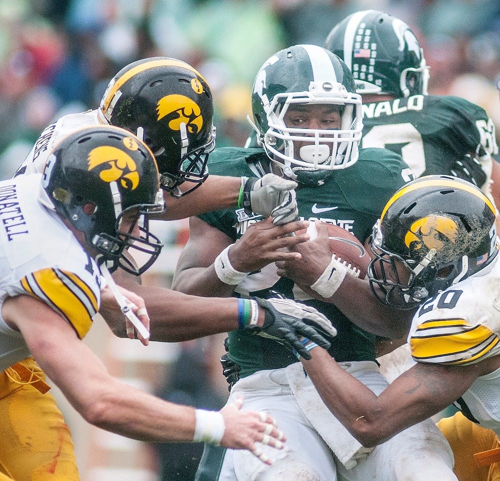 	<p>Iowa defenders overwhelm junior running back Le&#8217;Veon Bell. Bell had 29 carries during the game. The Spartans fell to the Hawkeyes on Saturday. Justin Wan/The State News</p>