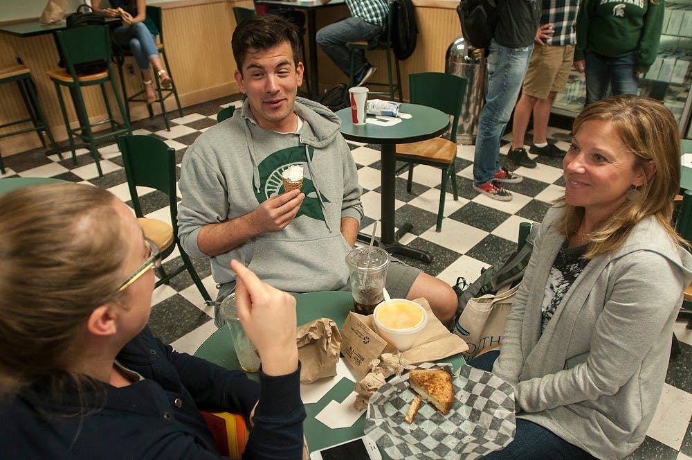 <p>Doctoral students Cassie Brownell, left, Jon Wargo, and Kristen White all enjoy their lunch together Sept. 30, 2014, at the MSU Dairy Store. Jon orders himself a vanilla ice-cream cone while Kristine enjoys a grilled cheese sandwich. Raymond Williams/The State News</p>
