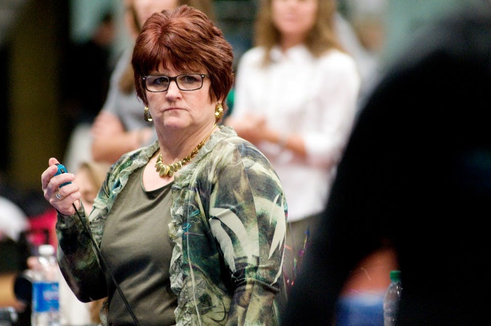 Head coach Kathie Klages keeps track of the time during a match against Pittsburgh Saturday at Jenison Field House. The MSU gymnastics team won with a score of 193.875-193.475. Jaclyn McNeal/The State News