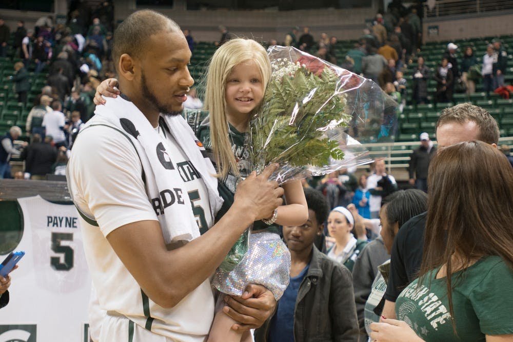 <p>Senior center Adreian Payne holds St. Johns, Mich. resident Lacey Holsworth, 8, on March 6, 2014, at Breslin Center after the game against Iowa during Senior Night. The Spartans defeated the Hawkeyes 86-76. Julia Nagy/The State News</p>
