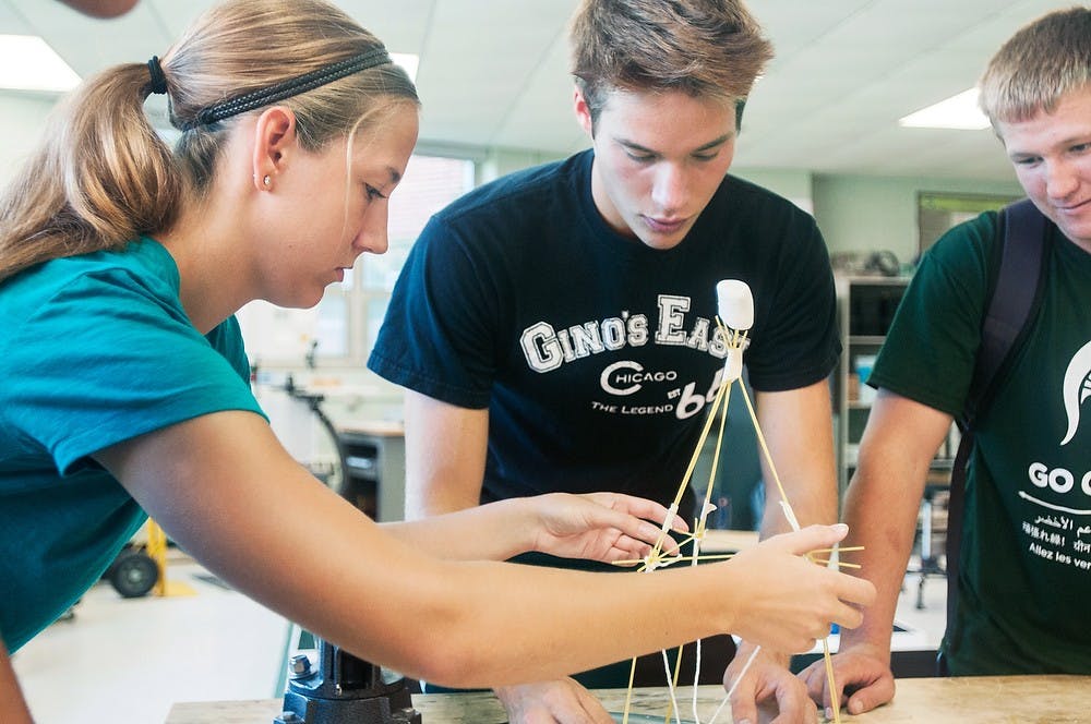 	<p>Chemical engineering freshman Amy Murphy tapes string to a pasta structure, held by Lyman Briggs freshman Phil Erickson during a <span class="caps">EGR</span> 100 course, Aug. 29, 2013, in G79 Wilson Hall. Students were creating structures made with pasta, tape, and string to hold up a single marshmallow. Danyelle Morrow/The State News</p>