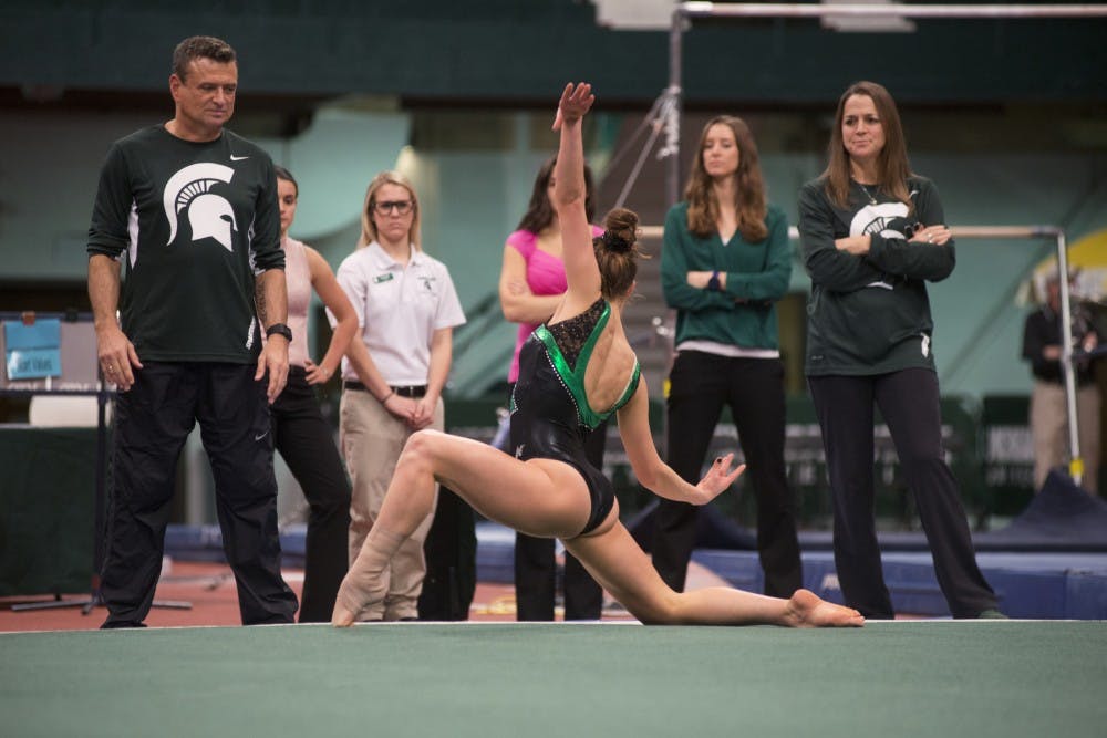 Gymnastics assistant coach Mike Rowe watches junior gymnast Elena Laogski perform on Jan. 15, 2016 at Jenison Field House. For the first time in school history the wrestling and gymnastics teams held a joint meet. 