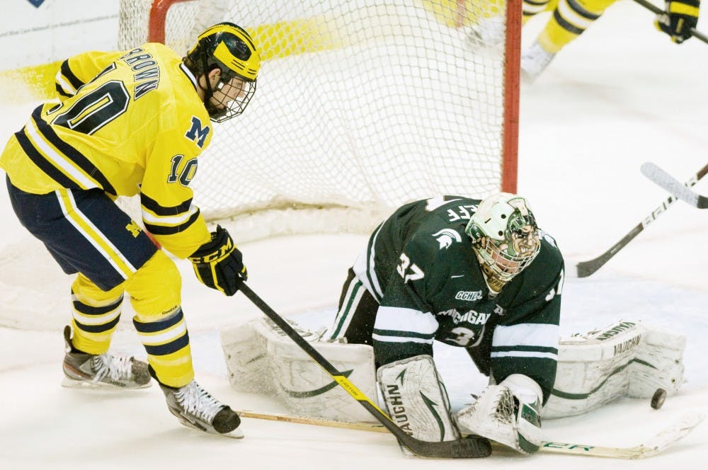 Michigan forward Chris Brown manages to hit the puck loose from sophomore goalie Will Yanakeff's glove. The Spartans fell to the Wolverines 3-2 in overtime Saturday night at Joe Louis Arena. Anthony Thibodeau/The State News