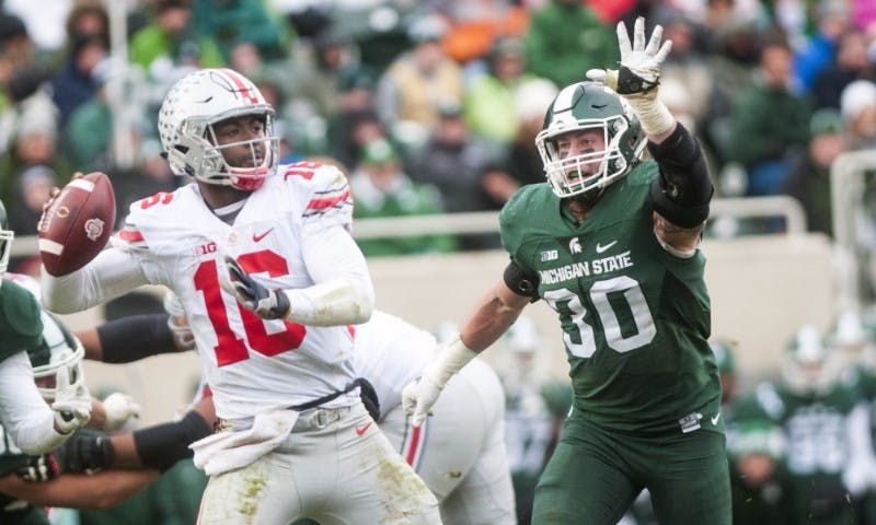 <p>Senior linebacker Riley Bullough attempts to block Ohio State quarterback J.T. Barrett (16) as he throws a pass during the game against Ohio State on Nov. 19, 2016 at Spartan Stadium. The Spartans were defeated by the Buckeyes, 17-16.</p>