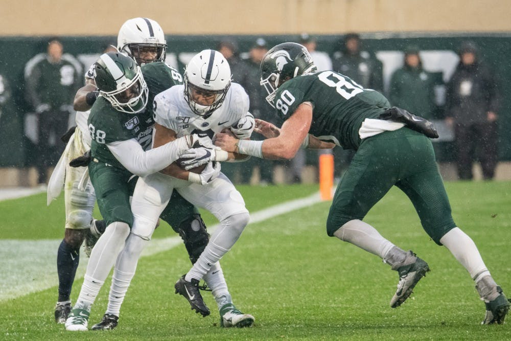 <p>Redshirt freshman tight end Trenton Gillison (88) and redshirt senior tight end Matt Seybert (80) tackle a Penn State defender after a blocked field goal during the game against Penn State Oct. 26, 2019 at Spartan Stadium. The Spartans fell to the Nittany Lions, 28-7.</p>