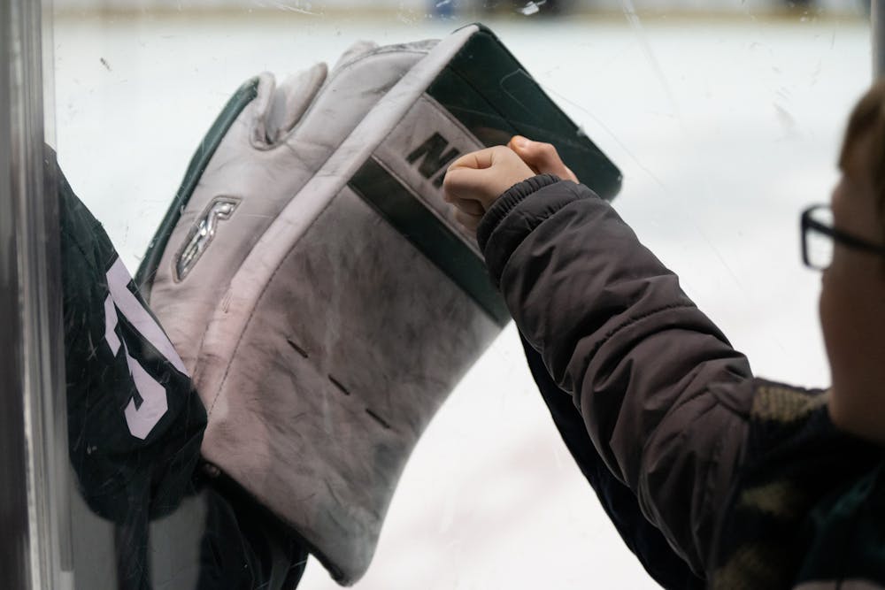 <p>Two young fans fist-bump MSU goaltender Jon Mor through the glass at at Compton Family Ice Arena in Notre Dame, IN on Friday, March 4, 2023. Over 5,000 fans attended the game, which was the second of a weekend-long series between MSU and Notre Dame.</p>