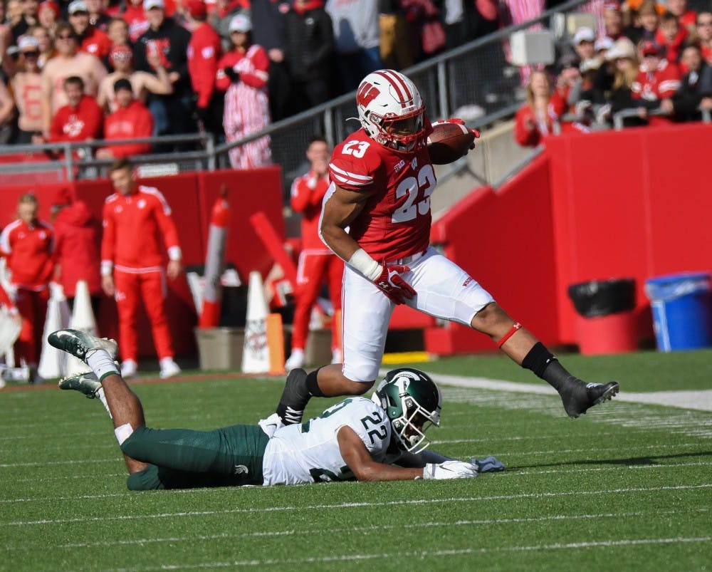 Wisconsin junior running back Jonathan Taylor (23) vaults over junior cornerback Josiah Scott (22) during the game against Wisconsin at Camp Randall Stadium on October 12, 2019. The Spartans lost to the Badgers 38-0. 