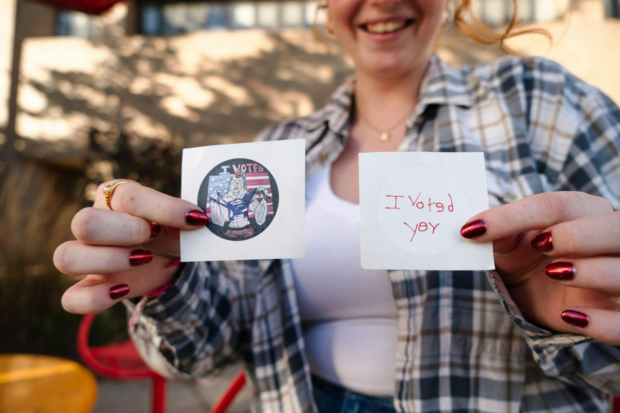 <p>Zoology junior Chapin Magee holds up her stickers after voting early at the WKAR studio in the Communication Arts and Sciences building on Oct. 23, 2024. Magee is an out-of-state student from D.C. "DC is super liberal and it's not here, so that's been something I've definitely had to get used to," she said.</p>