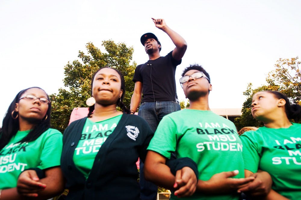 Social relations and policy senior Brandon Allen, center, speaks as social relations and policy sophomore Sirrita Darby, from left, social relations and policy junior Patricia Jackson, journalism junior Silver Moore and special education junior Genel Fowler link arms during the silent march and protest rally hosted by the Black Student Alliance and Iota Phi Theta fraternity on Thursday evening. The event was held in reaction to a string on racial incidents that occurred on campus within the past week. Several hundred students marched from Brody Complex before stopping behind Akers Hall. Lauren Wood/The State News