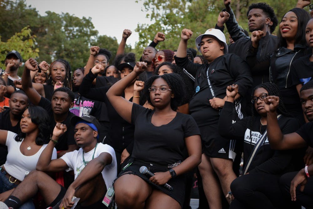 <p>Black Student Alliance MSU president Sharron Reed-Davis and others pose following her speech protesting the newly implemented block tuition at MSU during Spartan Remix behind Wells Hall on Sept. 5, 2019. Many students wore black to the event in support of the protest. </p>