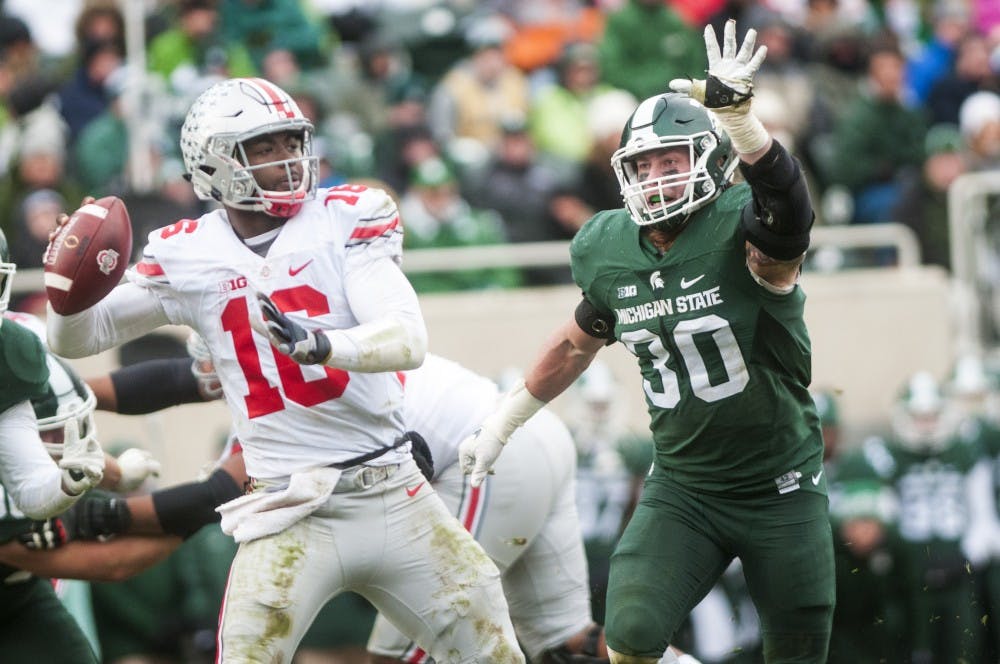 Senior linebacker Riley Bullough attempts to block Ohio State quarterback J.T. Barrett (16) as he throws a pass during the game against Ohio State on Nov. 19, 2016 at Spartan Stadium. The Spartans were defeated by the Buckeyes, 17-16.