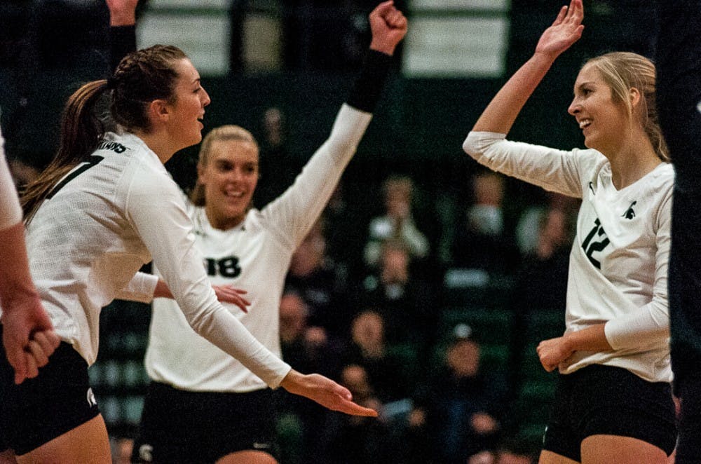 Senior middle blocker Alyssa Garvelink (17) and senior setter Rachel Minarick (12) high five after a play during the game on Nov. 1, 2017 at Jenison Fieldhouse. The Spartans fell to the Nittany Lions 3-1. 