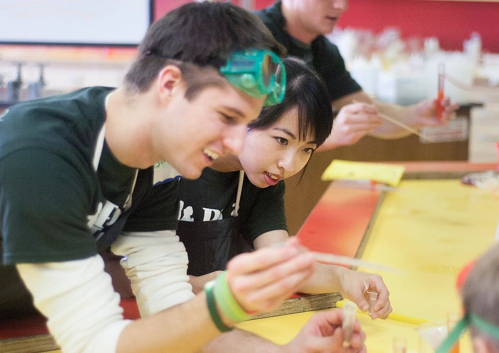 	<p>Physiology junior Man Wai Chau, right, and recent graduate Jimmy Poteracki, left,  help attendees of the PhUn Day extract <span class="caps">DNA</span> from strawberries at Impression 5 Science Center in Lansing on Saturday, Nov. 10, 2012. The event was hosted by the Michigan State University Department of Physiology in order to get kids interested in the field. Danyelle Morrow/The State News</p>