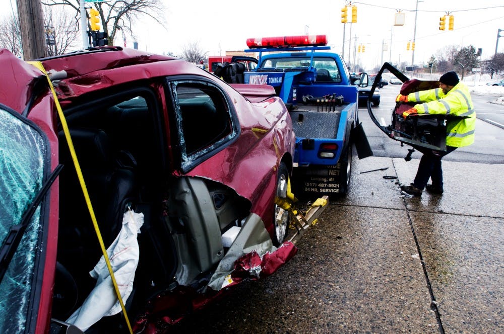 Northside Service & Towing employee Tim Taylor attempts to lift the door of a car onto the bed of his truck after the car crashed into a telephone pole at the corner of Michigan Ave. and Howard Thursday afternoon. Taylor has been working at Northside for thirty years and said accidents like this are very common, especially this time of year "I've seen so many accidents I don't pay attention them anymore, not even the fatalities" Taylor said. Matt Hallowell/The State News