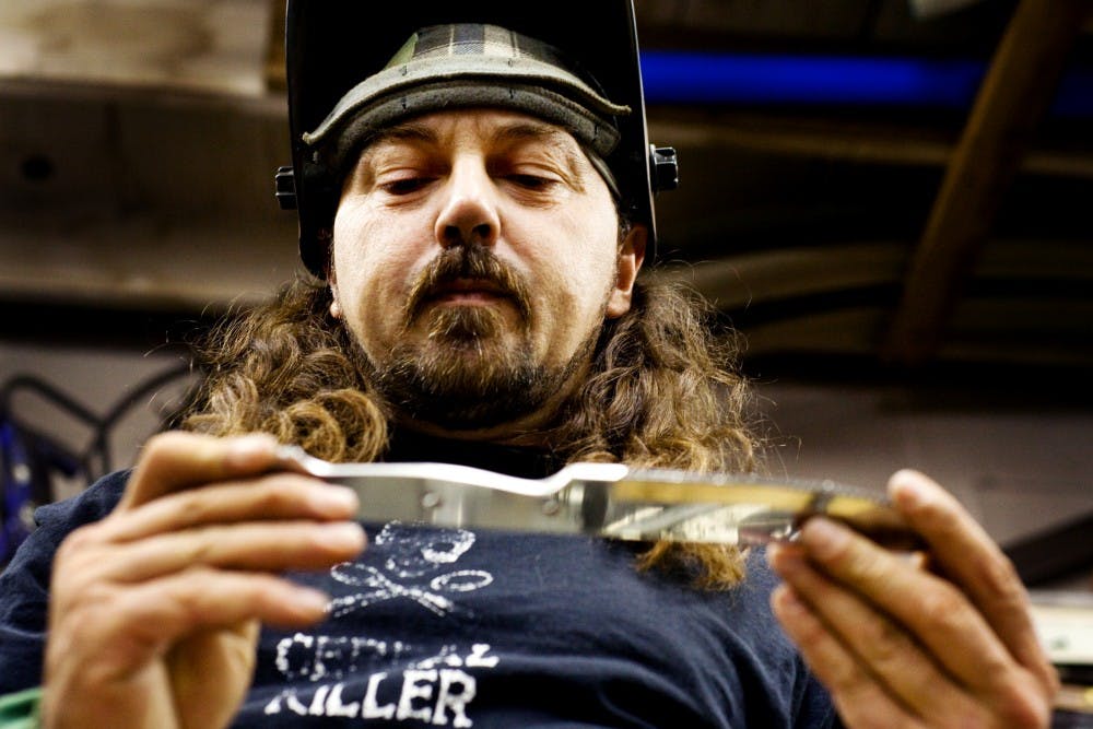 Lansing artist Tom Sheerin, or Scrap Art Guy, eyes a weld on a knife he used in a sculpture for this year's Art Prize Festival held in Grand Rapids Saturday, Sept. 10 at his Lansing studio. Sheerin initially started making small sculptures out of various sporting goods, but overtime his craft has evolved into creating large scale metal works. Matt Hallowell/The State News